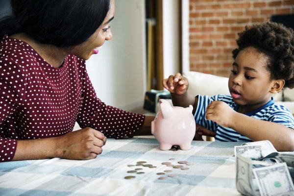 Mom and son saving money to piggy bank